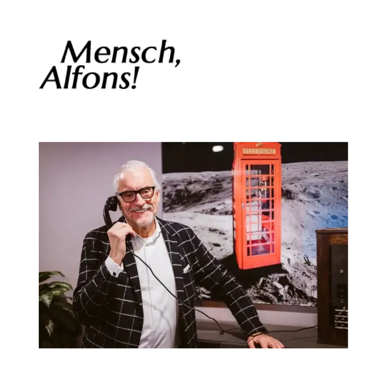 Alfons Bromkamp, Gründer der TRIPLE S Manufaktur und Speaker für Business-Ethik, am Telefon vor einer historischen Telefonzelle.